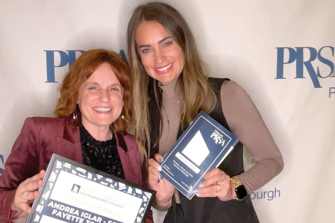 Andrea Iglar and Paula Willis holding certificate with PRSA Pittsburgh background in blue and white