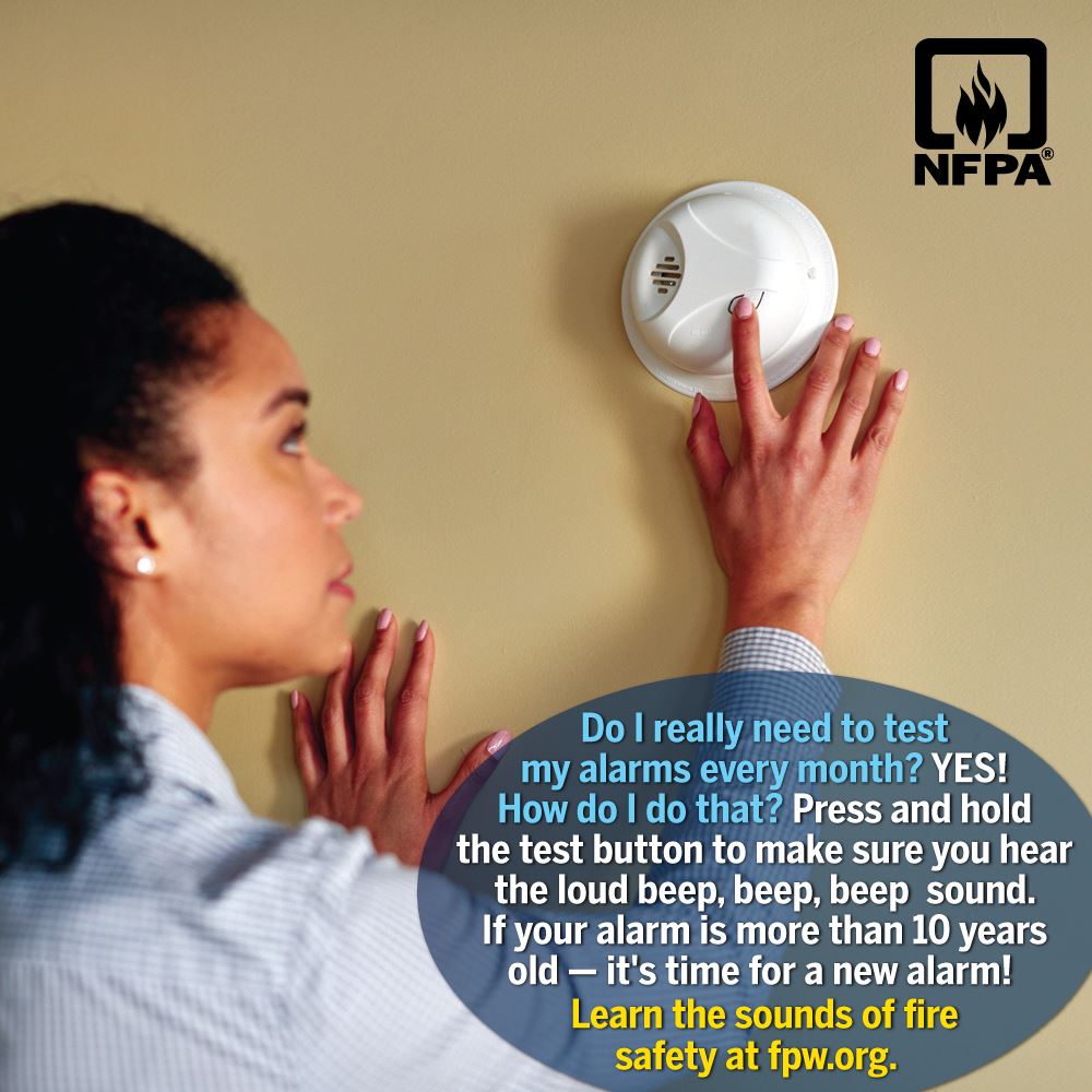 woman testing smoke alarm with message to test monthly